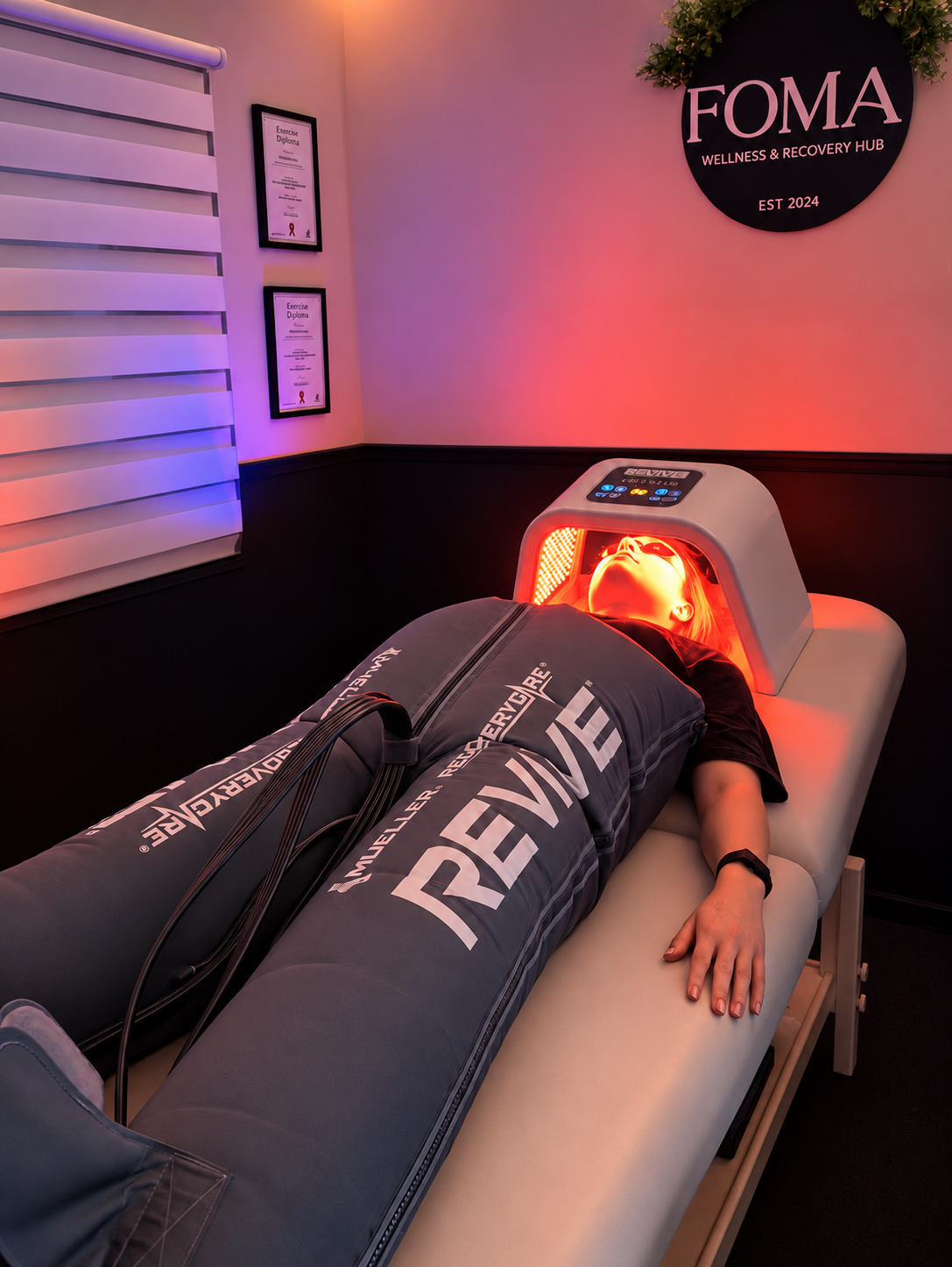 Client in a full-body lymphatic drainage compression suit with a red light LED mask at FOMA Wellness & Recovery Hub, Newtownabbey